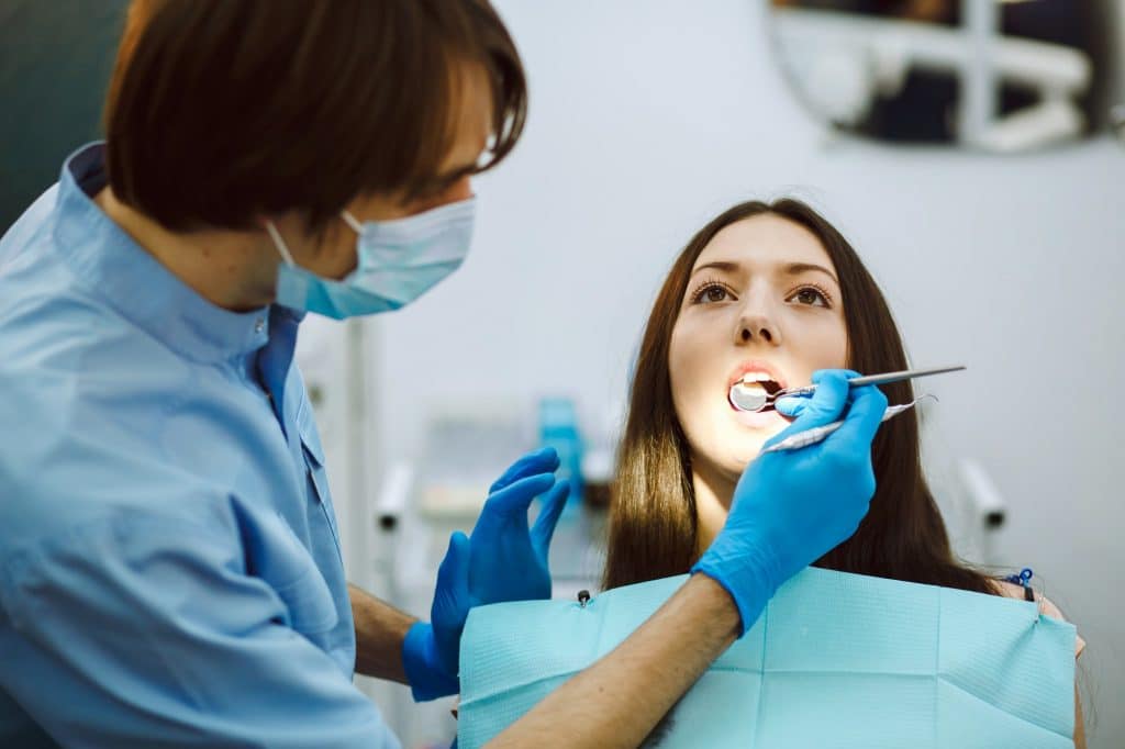 Inspection of the teeth of the girl with the help of a mirror