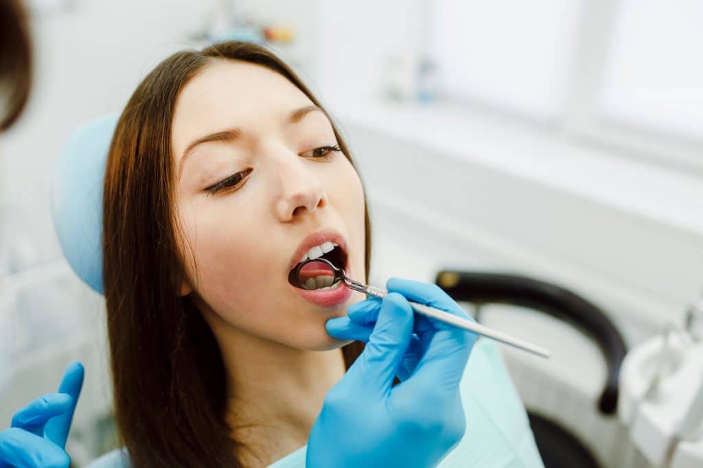 Inspection of the teeth of the girl with the help of a mirror